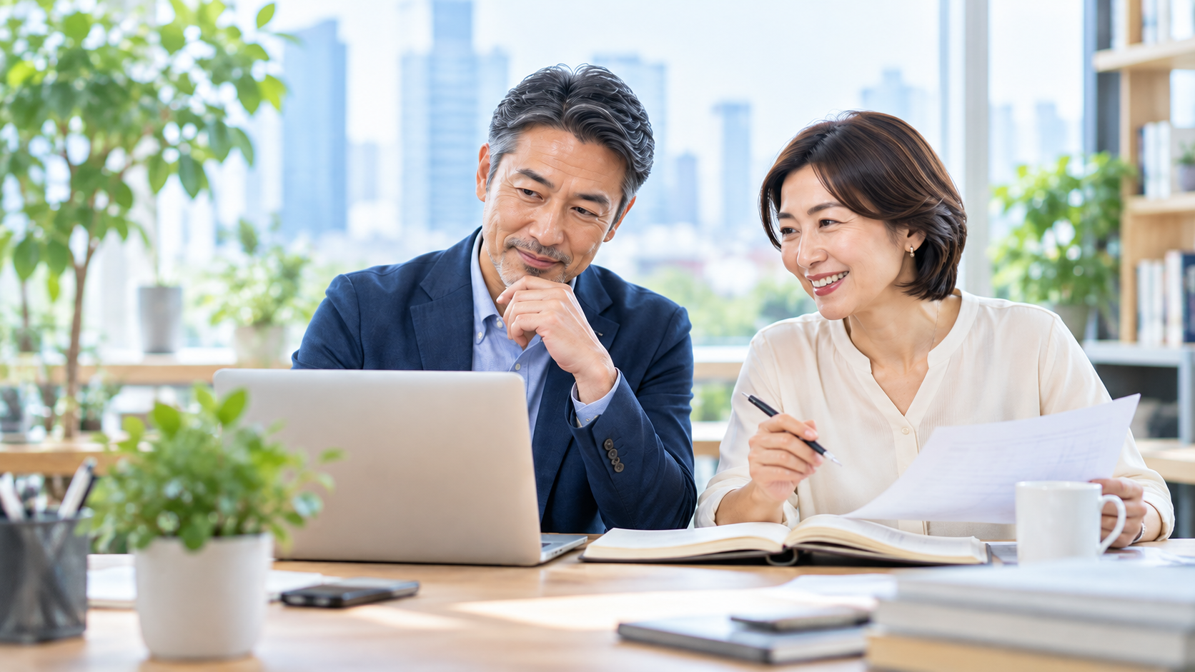 50代の男性と女性がパソコンや資料を使って仕事をしている様子